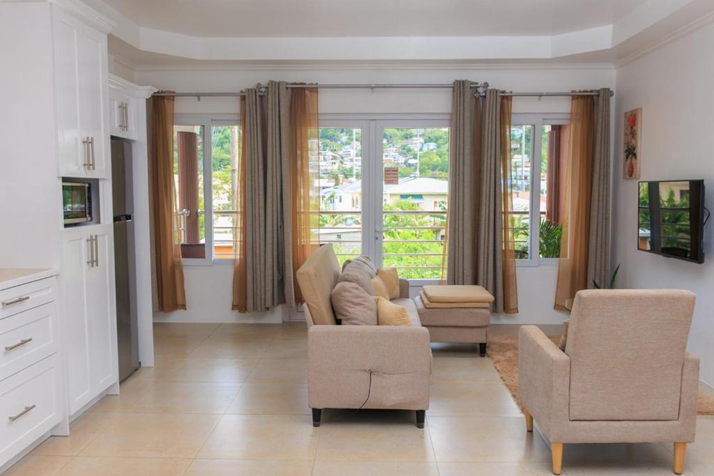 a living room with a couch and two chairs and windows at Agape Suites-Room 3- 1st Floor in Soufrière