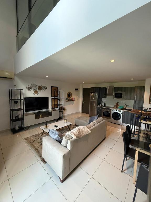 a large living room with a couch and a kitchen at Cozy Abode by Embassy Gardens in Cantonments