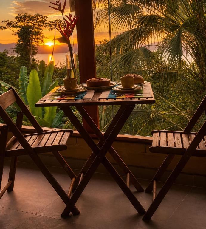 a wooden table with two chairs and a table with two cups at Chalés Mar & Mata Paraty in Paraty
