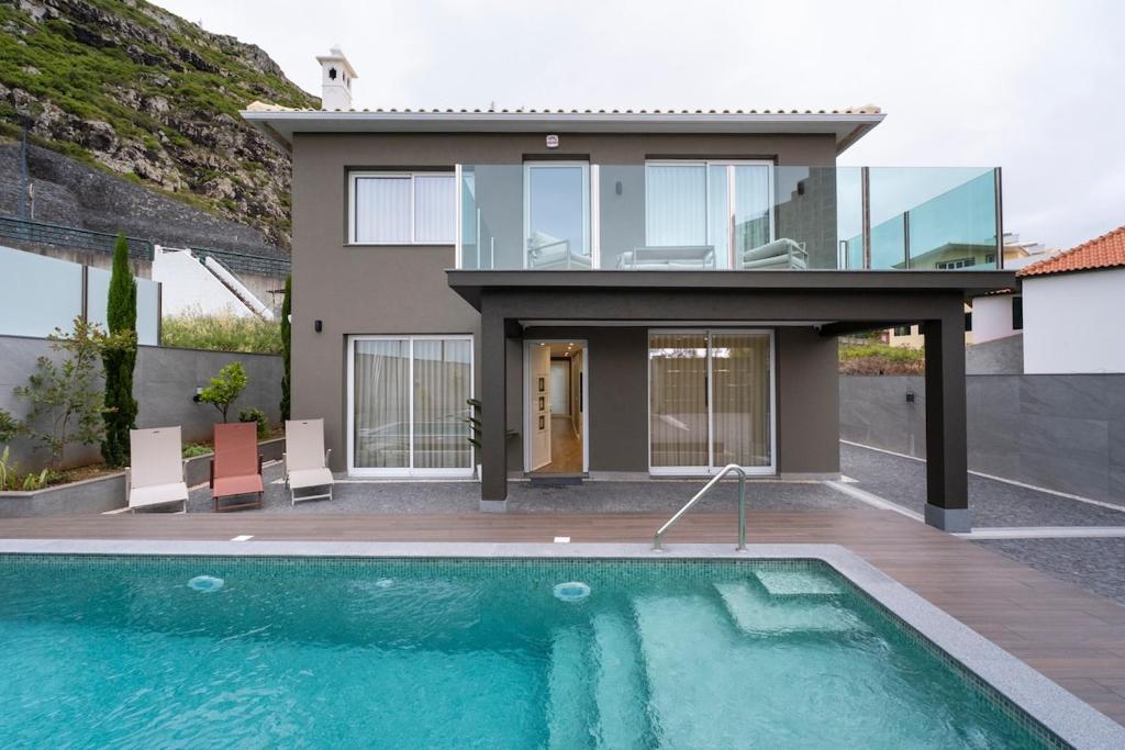 a house with a swimming pool in front of a house at Villa Machim - Heated Pool - View in Machico