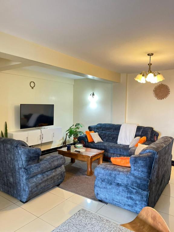 a living room with two blue couches and a television at Floma Homes in Nairobi