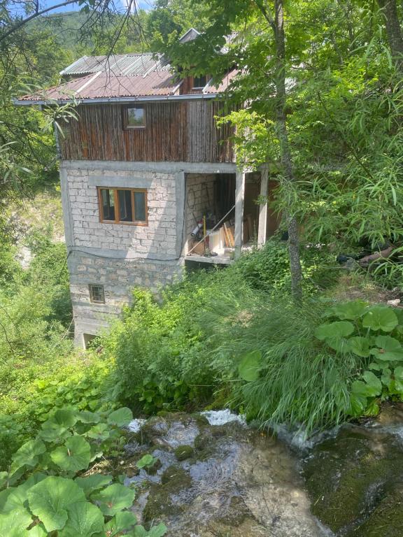 a stone house with a creek in front of it at Sopotnica - Apartman na vodopadima in Prijepolje