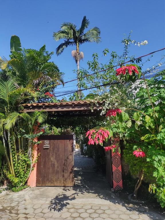 a garden with a gate and flowers and a palm tree at Aldeia Itamambuca Chalé Camping Ubatuba in Ubatuba