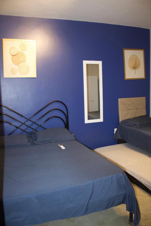 a bedroom with two beds and a blue wall at APT térreo completo - 2 Quartos - 2 Ar-condicionados, Cozinha, Garagem, WI-FI- Maurício Nassau, Perto de tudo in Caruaru