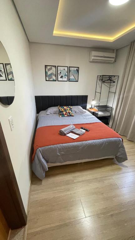 a bedroom with a bed with a red blanket at Villa Serena Garden - Quarto Cama Queen - Banheiro Compartilhado in Cascavel