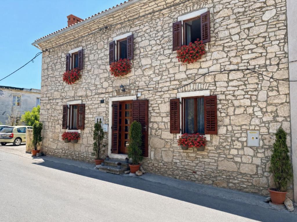 a stone building with flowers on the front of it at Freya's Apartments Medulin in Medulin