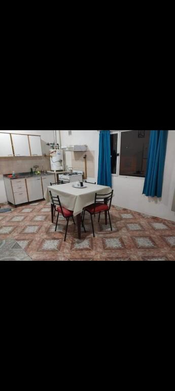 a table and chairs in a room with blue curtains at Alojamiento LA ROSALIA in Yacimiento Río Turbio