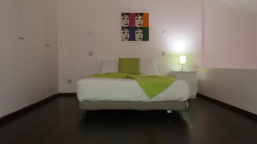 a bedroom with a bed with a green blanket on it at Serpa's Apartments in Porto