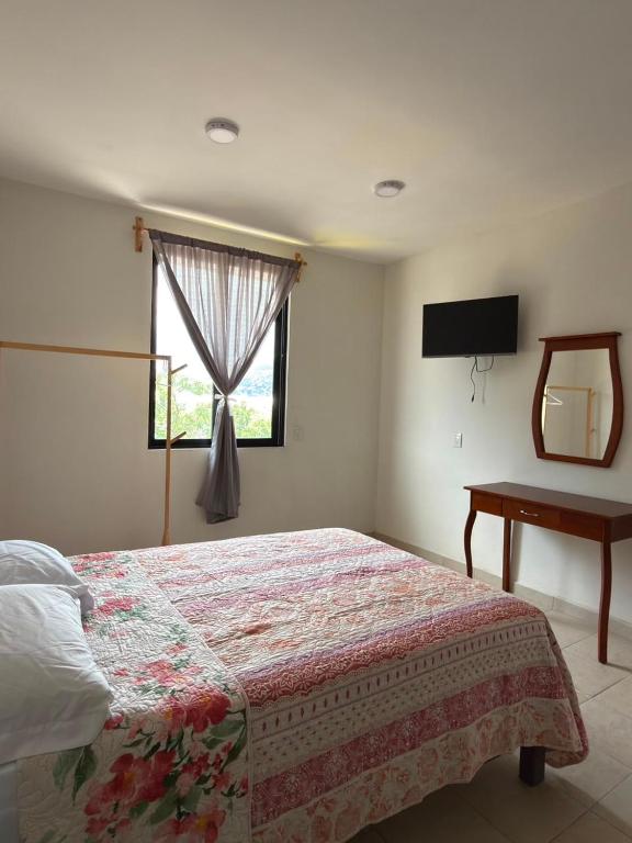 a bedroom with a bed and a window and a table at Casa Flor in San Antonio de la Cal