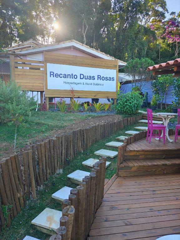 a sign for aresoria duedros house with a wooden deck at Recanto Duas Rosas in Venda Nova do Imigrante