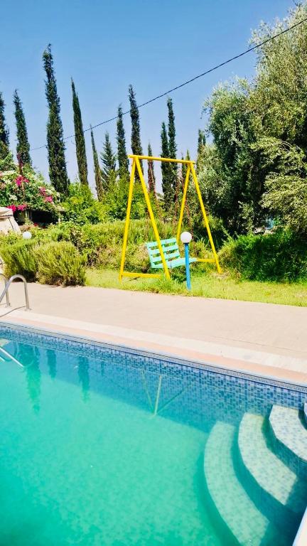 a yellow swing next to a swimming pool at Villa à Marrakech in Oulad Sidi Cheïkh
