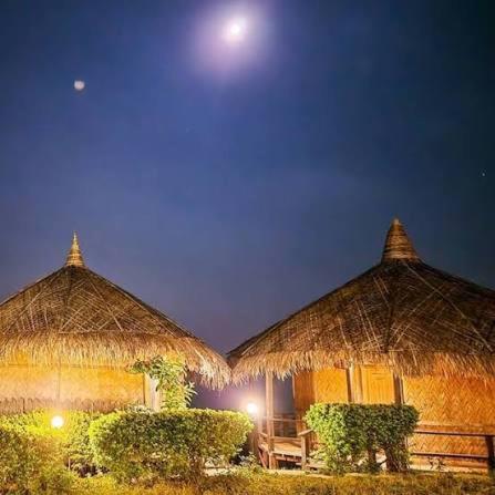 two huts with straw umbrellas at night at SA Housing 2 in Rangpur