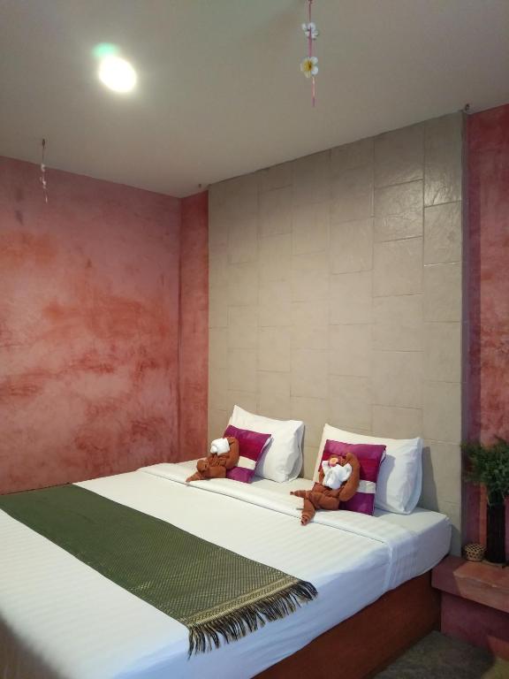 two teddy bears sitting on a bed in a room at THAMONWAN hostel in Cha Am
