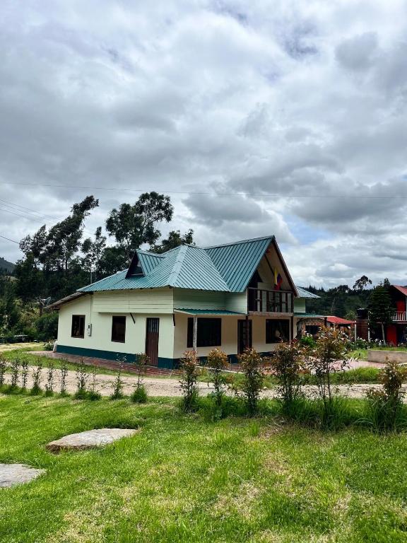 a house with a green roof on a field at Cabaña La Colina in Sutatausa