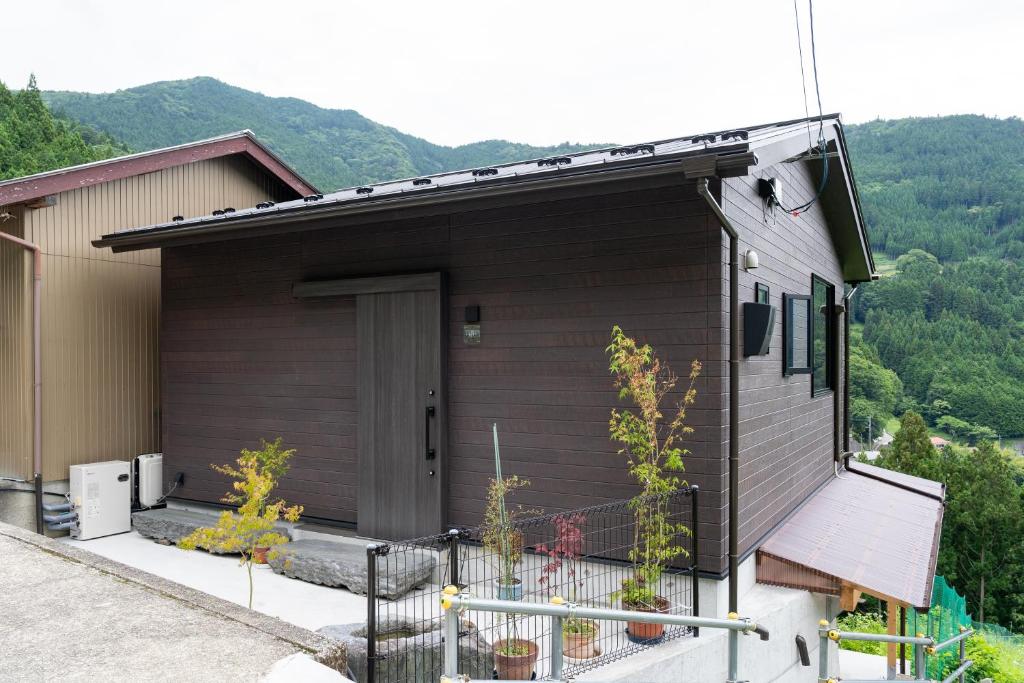 a brown house with a fence in front of it at Tiny House Iyashirochi Kaze in Miyoshi