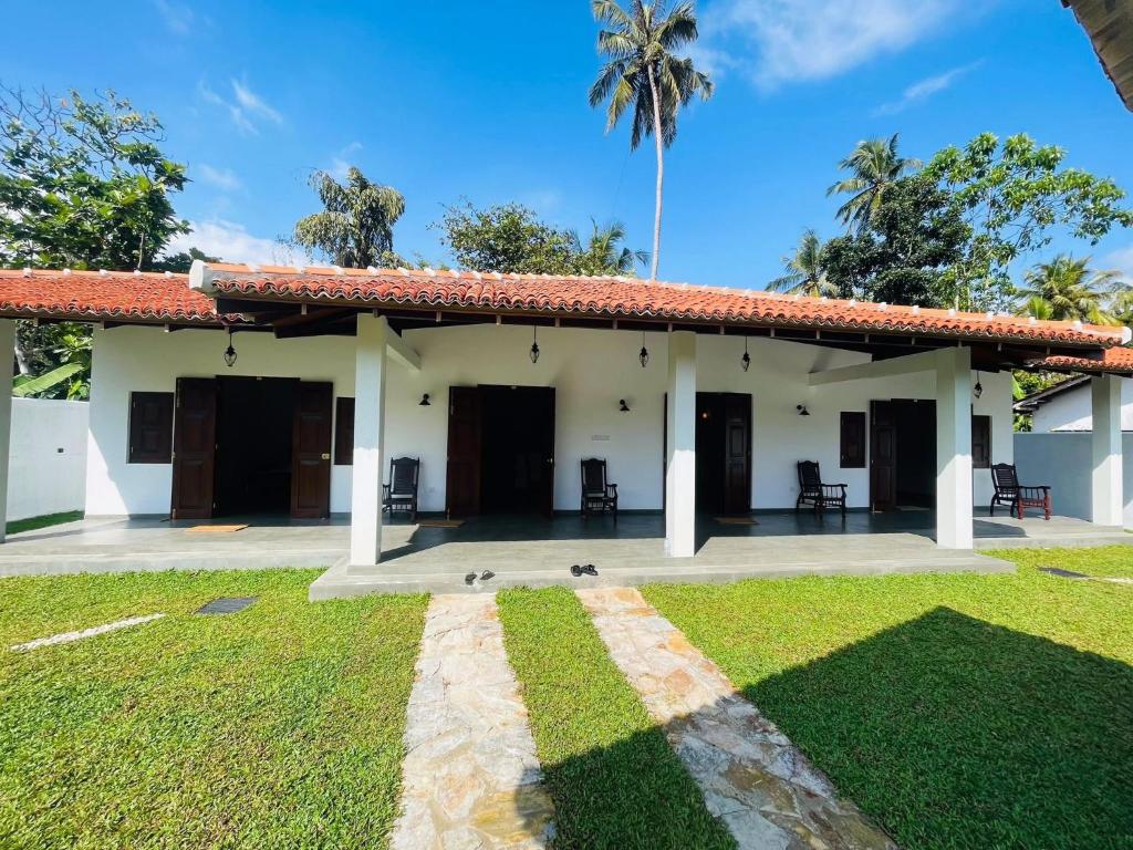a white house with a palm tree in the background at Legacy Weligama - 8 min to Weligama Beach in Weligama