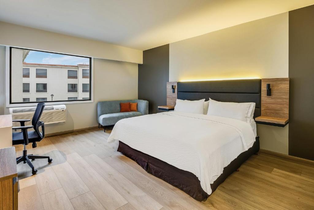 a bedroom with a large bed and a desk and a chair at Fiesta Inn Monterrey la Fe in Monterrey