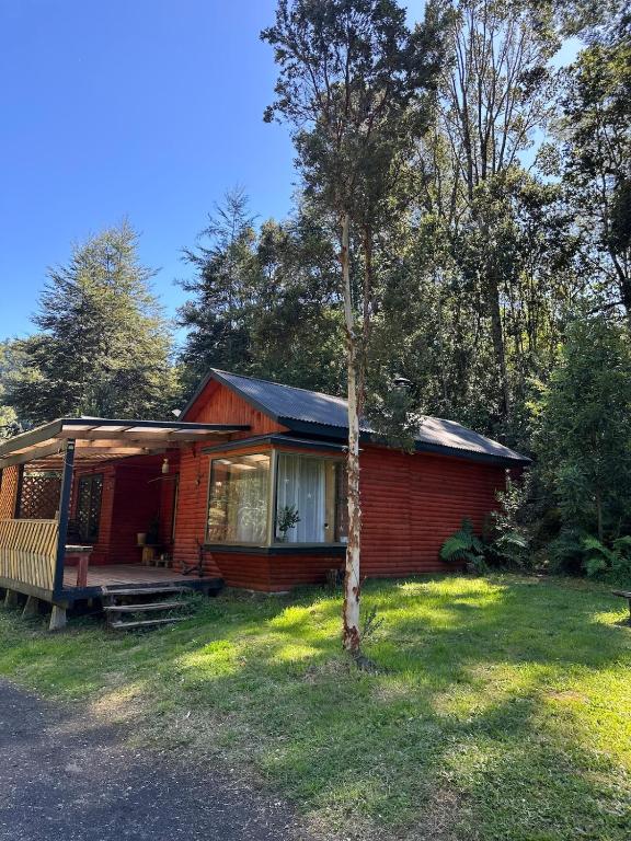 a red house with a tree in front of it at Casa Salto Pichi Ignao in Lago Ranco
