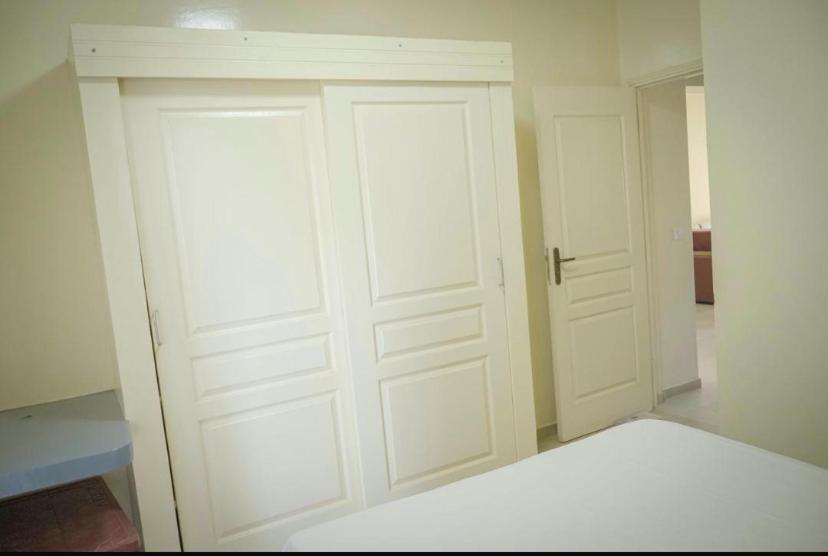 a bedroom with a white closet with two doors at Immeuble carrefour 2 in Ngaparou