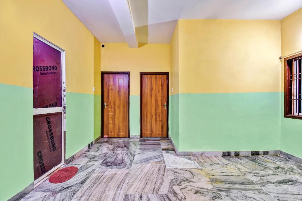 an empty room with green and yellow walls and wooden doors at OYO 80514 Moody Moon in Bārang