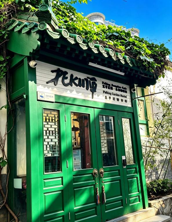a green building with a sign on top of it at Peking Station Hostel in Beijing