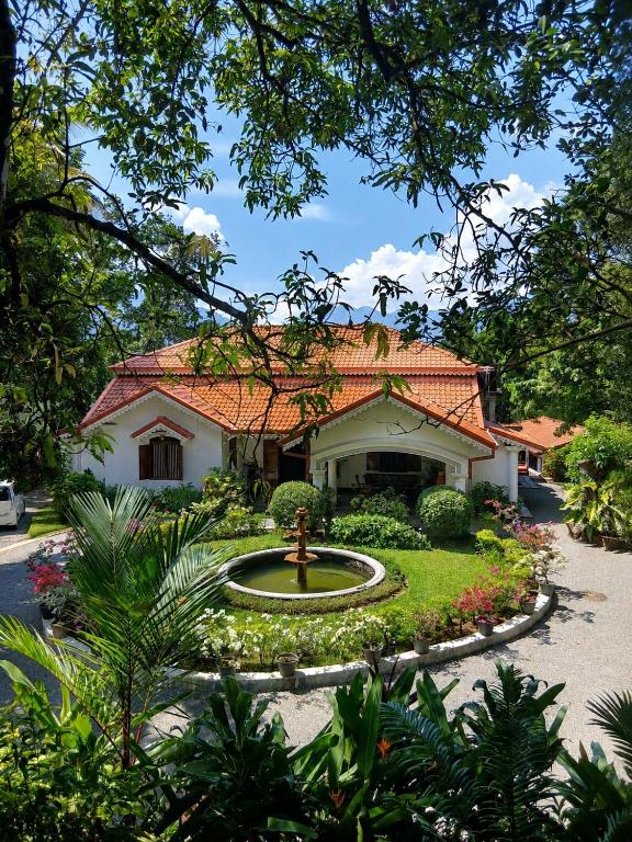 a house with a fountain in the middle of a garden at Kithulvilla Holiday Bungalow in Kitulgala