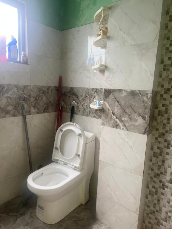 a bathroom with a toilet with the seat up at Lama home in Bālāju