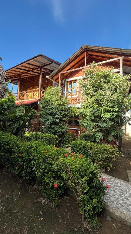 a large wooden house with bushes in front of it at Mi Ranchito Capurganá in Capurganá