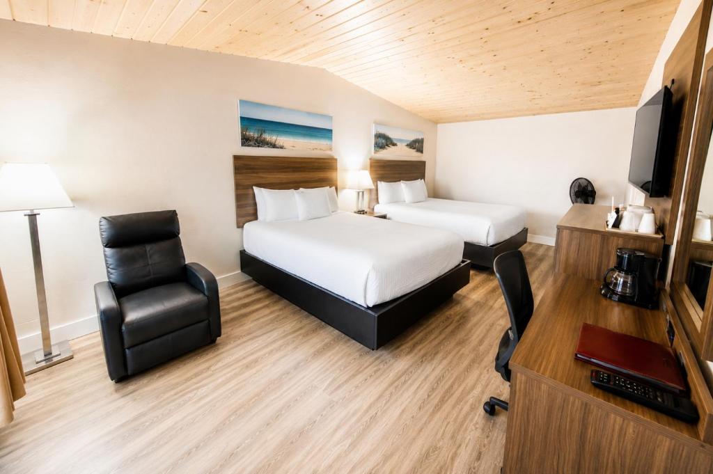 a hotel room with a bed and a desk and a tv at Anchor Bay Inn near Winchester Bay in Reedsport