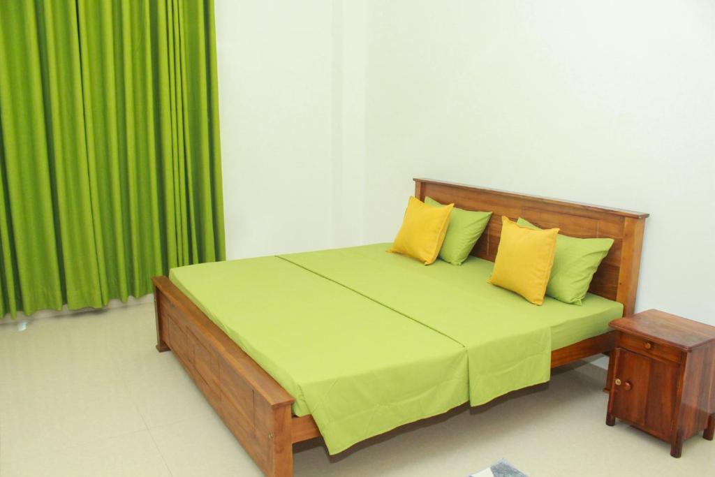 a bedroom with a bed with yellow pillows and green curtains at Villa Deniyaya in Deniyaya