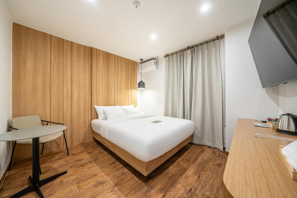 a bedroom with a large white bed and a desk at 구리 호텔 옐로 in Guri