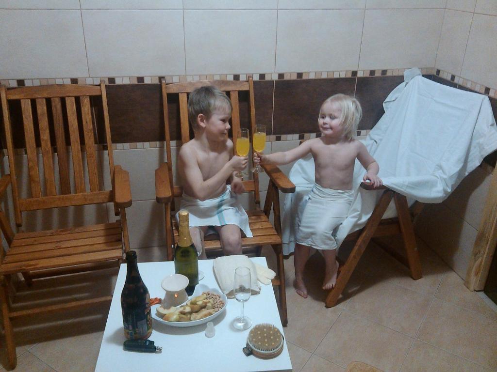 two children are sitting in chairs with wine glasses at Apartmány Kuřátko in Benecko