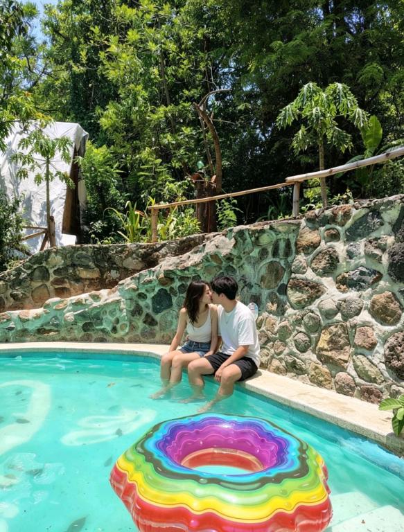 a man and a woman sitting next to a swimming pool at Glamp de Lujo Teques Granja El Sol in Xoxocotla