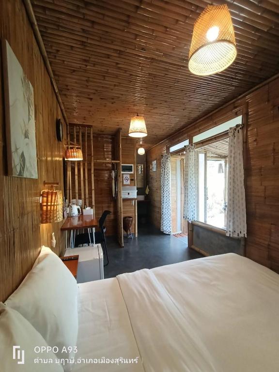 a bedroom with a bed and a desk in a room at สวนเกษตรรักษ์ไผ่ Bamboo Conservation Farm in Surin