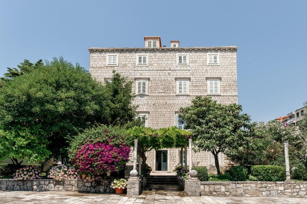 a large brick building with trees and flowers at The Old Town Hostel-Villa Gradac in Dubrovnik