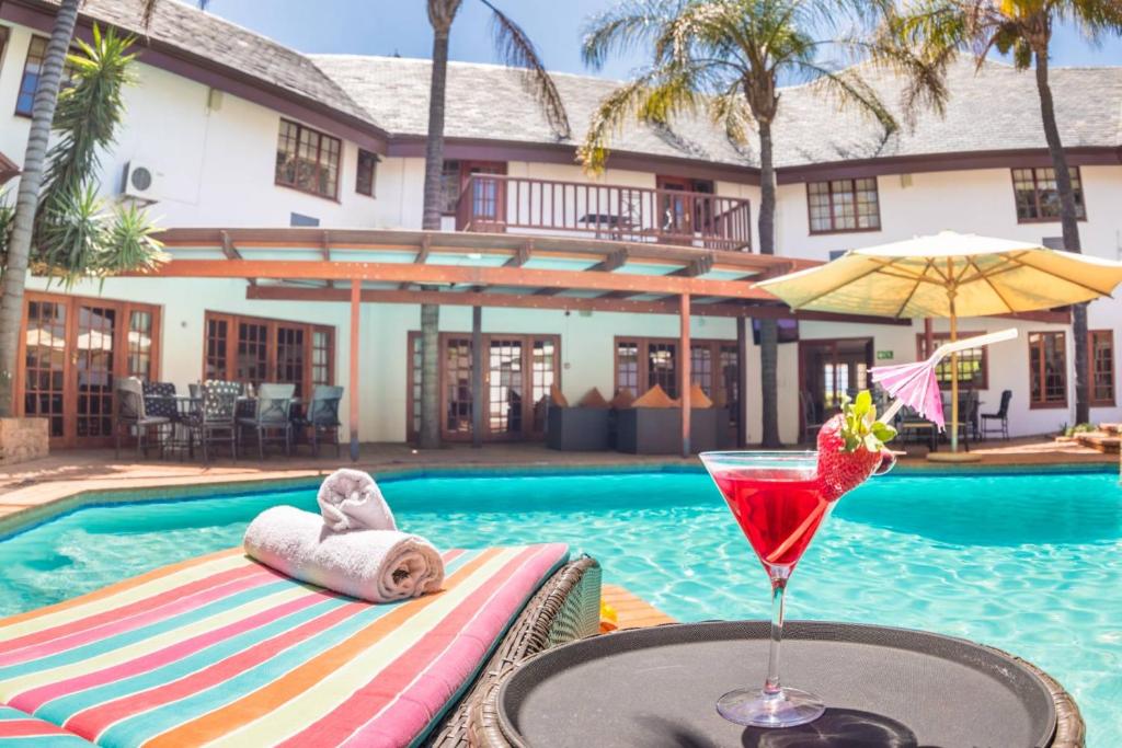 a drink on a table next to a swimming pool at Constantia Hotel and Conference Centre in Midrand