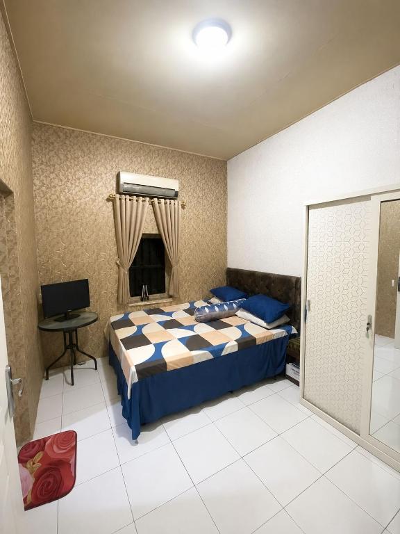 a bedroom with a bed and a desk and a television at Guest House Brahu Syariah in Trowulan