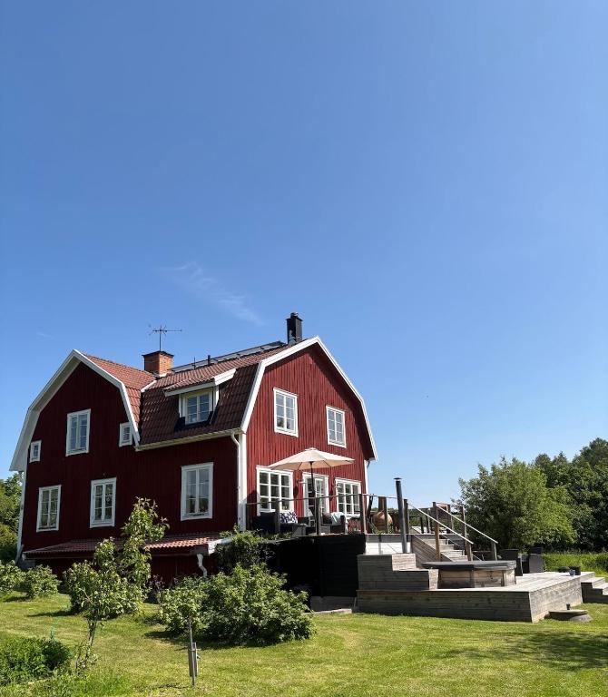 a large red house with a porch on a lawn at Sjötomt med bastuflotte & badtunna - lantlig idyll in Vingåker