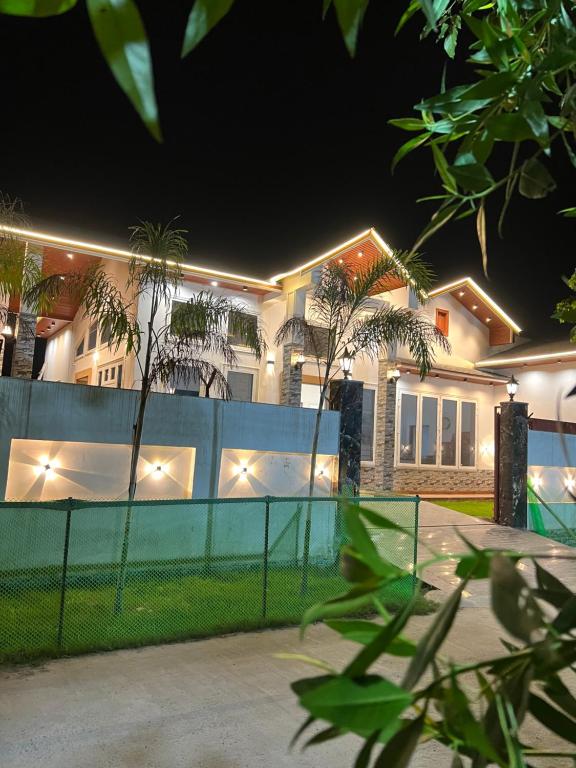 a house with a fence in front of it at night at The Palm Grove Farm Villa in Greater Noida