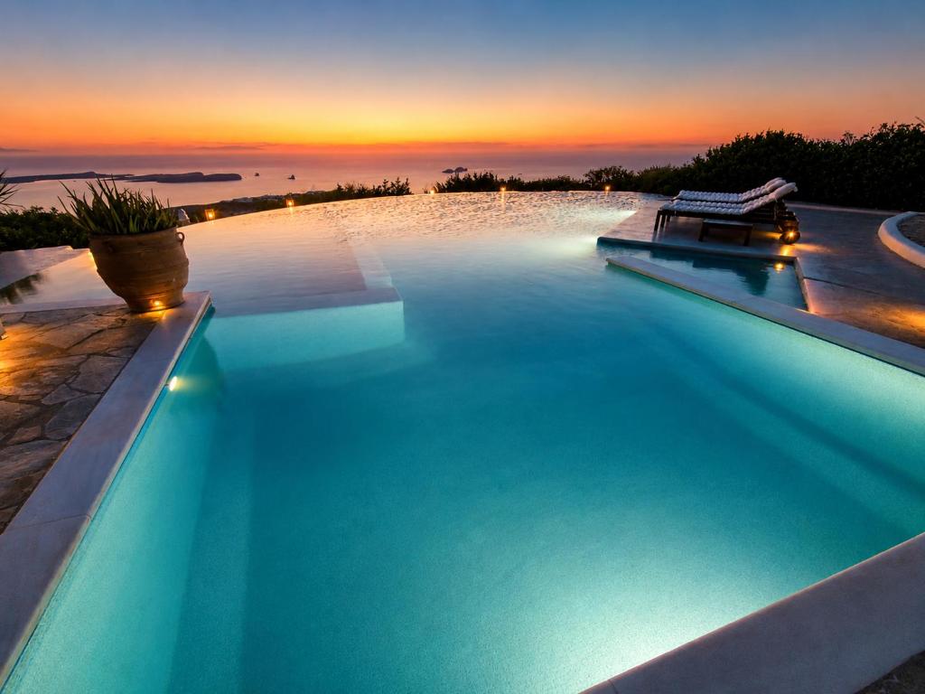 a large swimming pool with a sunset in the background at Villa Pastorale Paros in Parikia