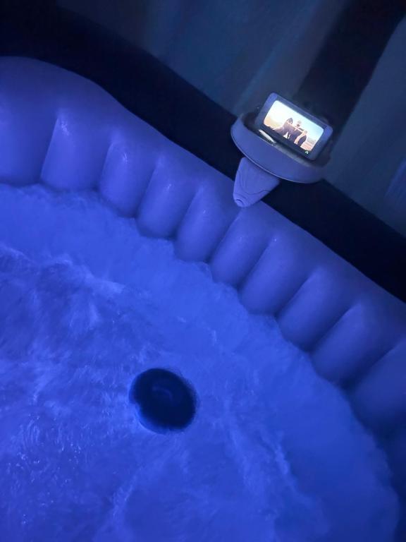 a blue room with a tub with a cell phone at Jacuzzi Clim table de massage jardin et barbecue au cœur de Perpignan in Perpignan