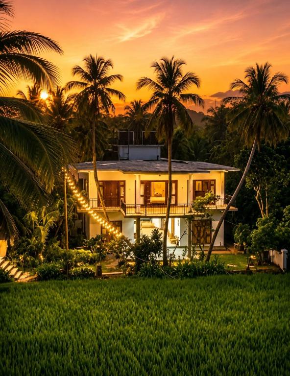 a house with palm trees in front of a sunset at Danketiya Palace in Ahangama