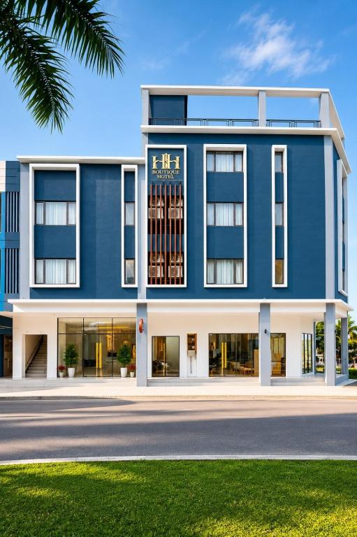 a blue building with a palm tree in front of it at H&H Boutique Hotel in Cukai