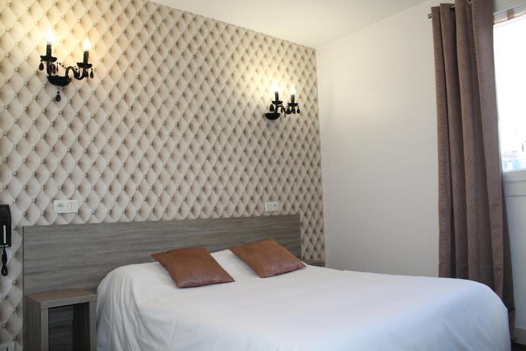 ein Schlafzimmer mit einem Bett mit zwei Kissen darauf in der Unterkunft Hôtel Beaulieu in Clermont-Ferrand