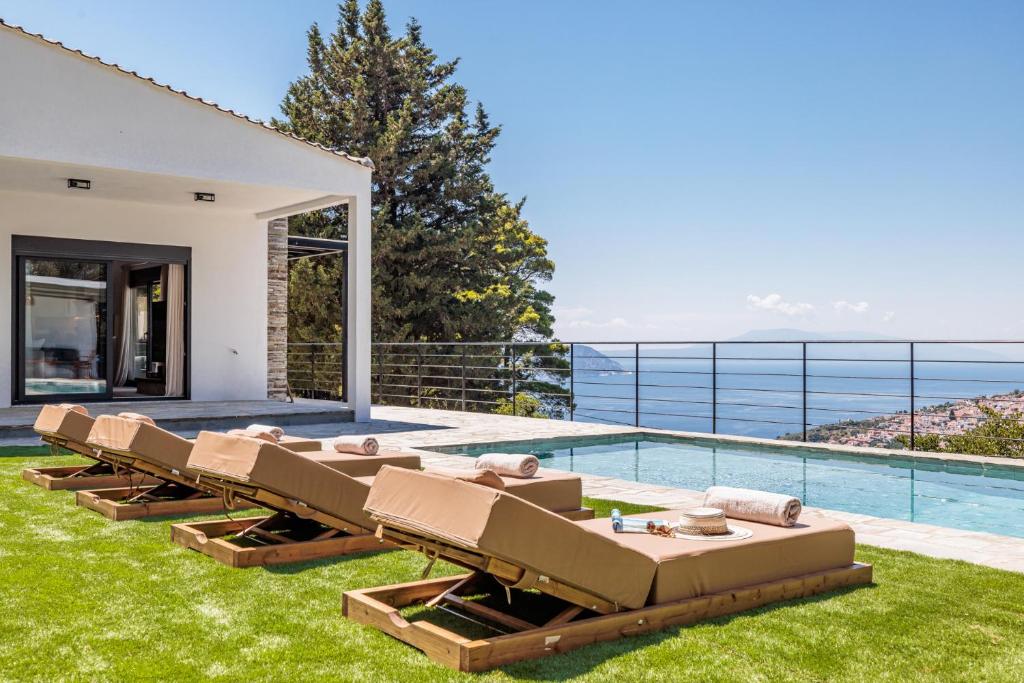 a group of chairs sitting on the grass next to a swimming pool at Villa Theofilos in Glossa