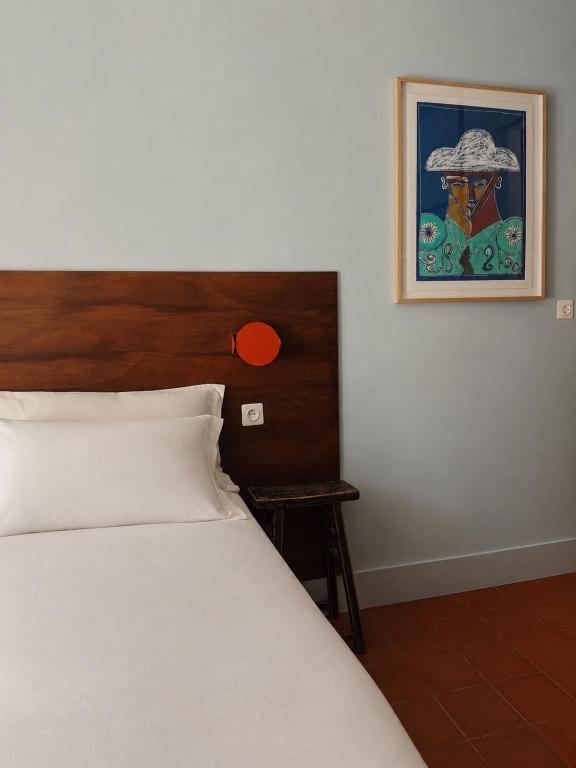 a bedroom with a bed and a picture on the wall at Hôtel Le Voltaire in Arles