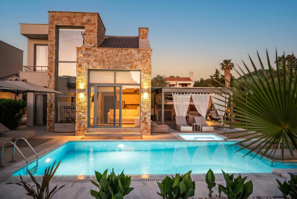 a swimming pool in front of a house at Ocean Private Villas - Pefkochori Halkidiki in Pefkochori