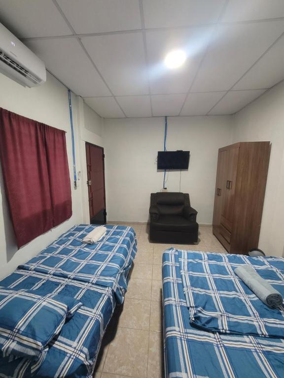 a room with two beds and a chair in it at Hostal viroleño in Zacatecoluca