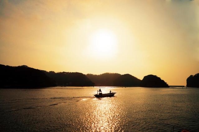 two people in a boat on the water at sunset at トラストメゾン西伊豆 in Ukusu