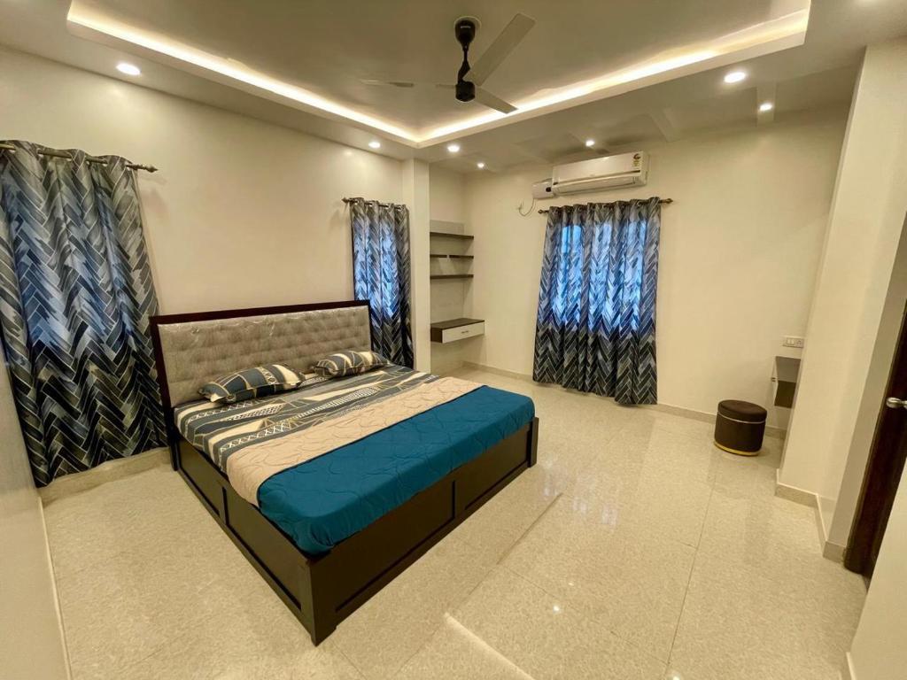 a bedroom with a bed with blue sheets and windows at Tropical Haven in Panaji